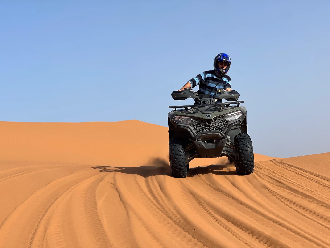 Rider on a quad bike on a smooth dune crest in Erg Chebbi, Merzouga