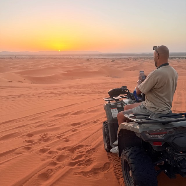 Rider on a quad watching the sun set over the Merzouga dunes